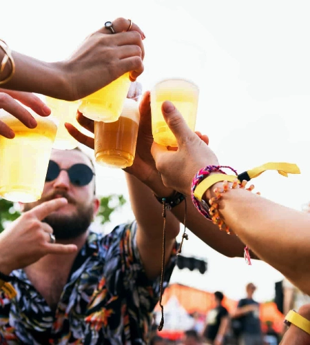Anstoßende Festivalbesucher mit bedruckten Festivalarmbändern am Handgelenk